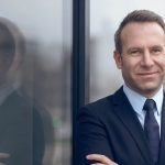 confident man folding both hands and standing by wall